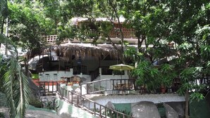 A restaurant with outdoor seating, a thatched roof, and a stone staircase leading to the seating area. - Hostal Restaurante y Spa Mama Neyumun (Santa Marta)