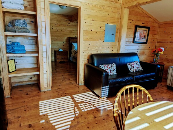 Ein gemütliches Holzhaus-Interieur mit einer schwarzen Ledersofa, Holzböden und einem Essbereich mit Tisch und Stühlen.