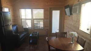 A cozy cabin interior with a wooden dining table, chairs, a sofa, and a small coffee table. - Kingman KOA (Kingman)