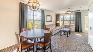 Una habitación de hotel con una mesa redonda de comedor, dos sofás, una mesa auxiliar y una araña.