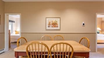 A dining room with a wooden table and chairs, a framed picture on the wall, and a thermostat.