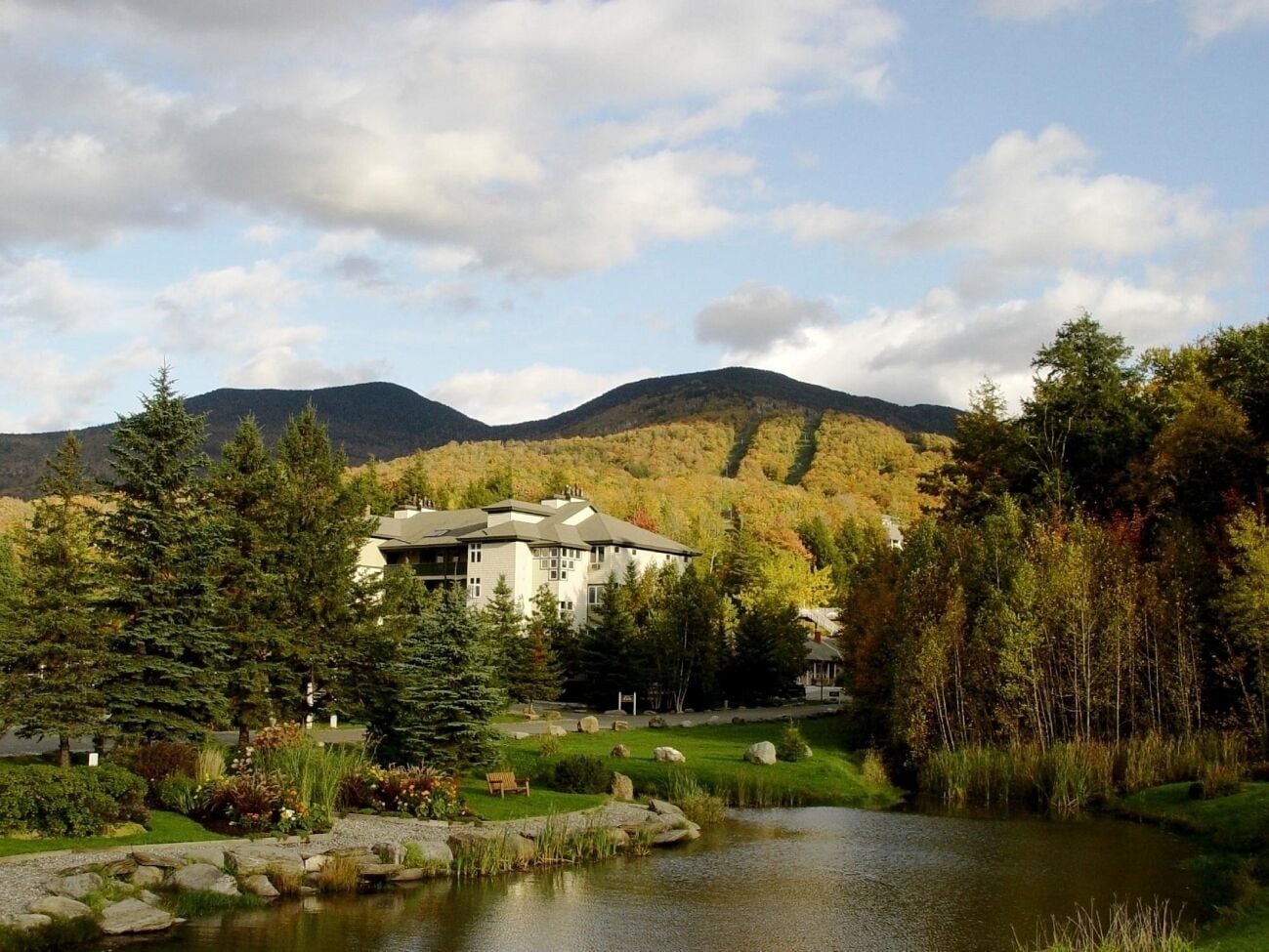 A lodge with a large building surrounded by trees and a lake.