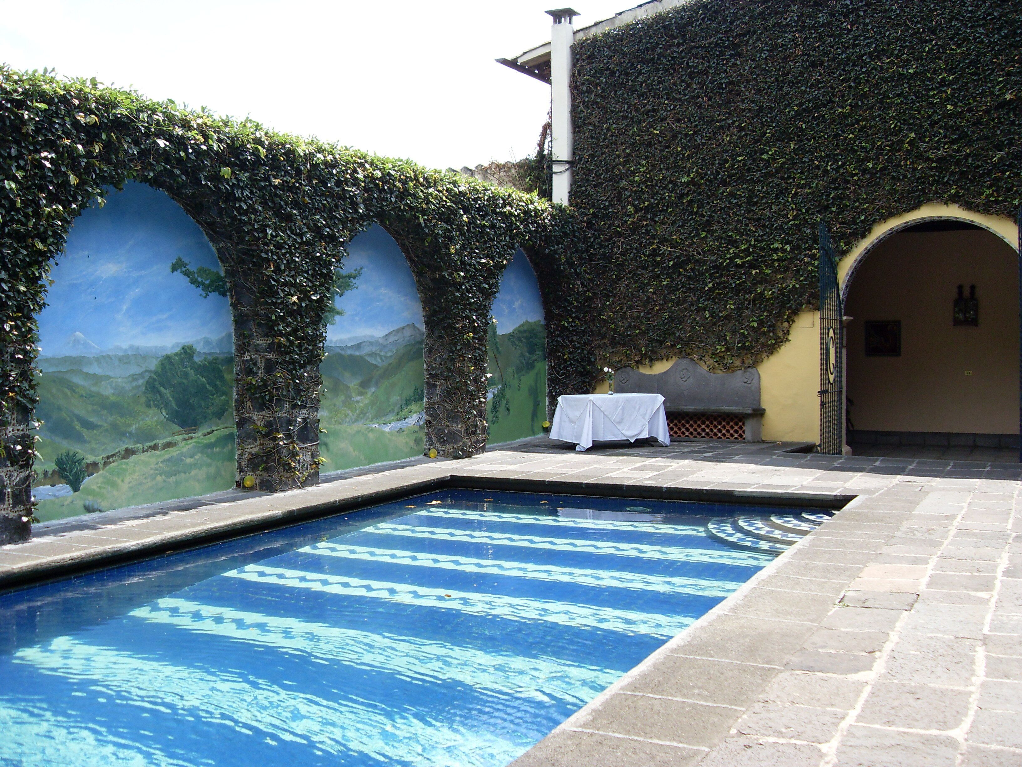 Una piscina con vistas a un paisaje montañoso a través de un ventanal de arco.