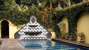 Una piscina con un muro decorativo de azulejos y una fuente.