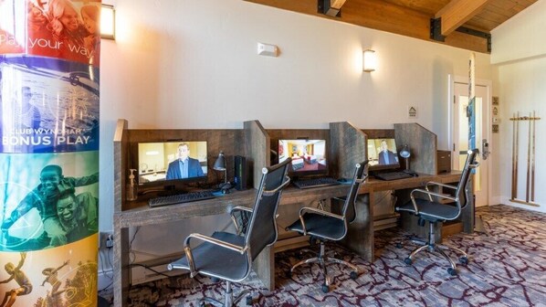 Una habitación con varias estaciones de trabajo, escritorios de madera y sillas.