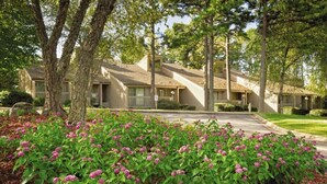 A residential area with multiple two-story houses, a well-maintained lawn, and flowering shrubs in the foreground. - Wyndham Resort At Fairfield Bay - 1 Bedroom Deluxe (Fairfield Bay)