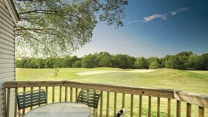 A wooden deck with a table and chairs overlooking a golf course. - Wyndham Resort At Fairfield Bay - 1 Bedroom Deluxe (Fairfield Bay)