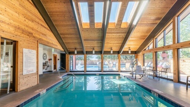 An indoor swimming pool with wooden walls and large windows.