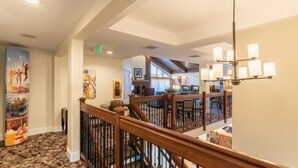 A hotel lobby with a staircase, a chandelier, and artwork on the walls.