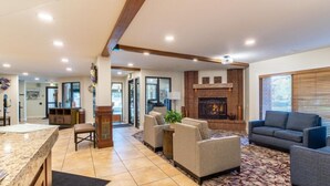 A spacious living room with a fireplace, comfortable seating, and a kitchen area.