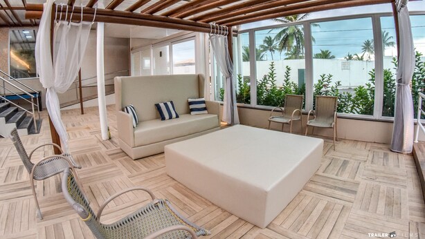 A room with a bed, a sofa, and wicker chairs. There is a staircase and a view of palm trees outside. - Farol Plaza Hotel (Aracaju)