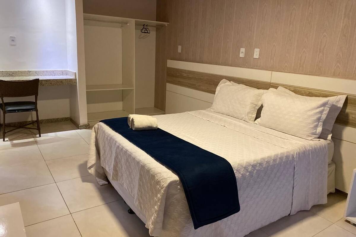 Hotellihuone, jossa on sänky, tuoli ja vaatekaappi.