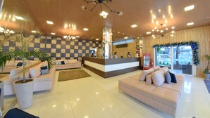 A hotel lobby with a reception desk, sofas, potted plants, and a checkered wall. - Farol Plaza Hotel (Aracaju)