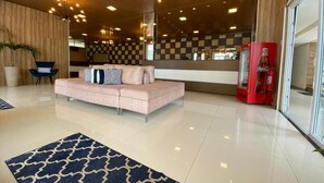 A modern lobby with a plush pink sofa, a patterned rug, and a Coca-Cola vending machine. - Farol Plaza Hotel (Aracaju)