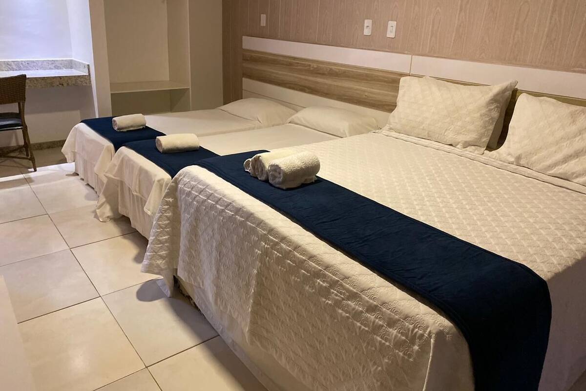 Hotellihuoneessa on kaksi sänkyä, joissa kummassakin on valkoinen peitto ja tummansininen pääty. Huoneen nurkassa on tuoli ja pieni pöytä.