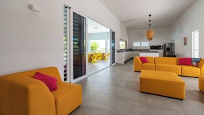 Ein modernes Wohnzimmer mit gelben Sofas und einer hellen Küche im Hintergrund.
