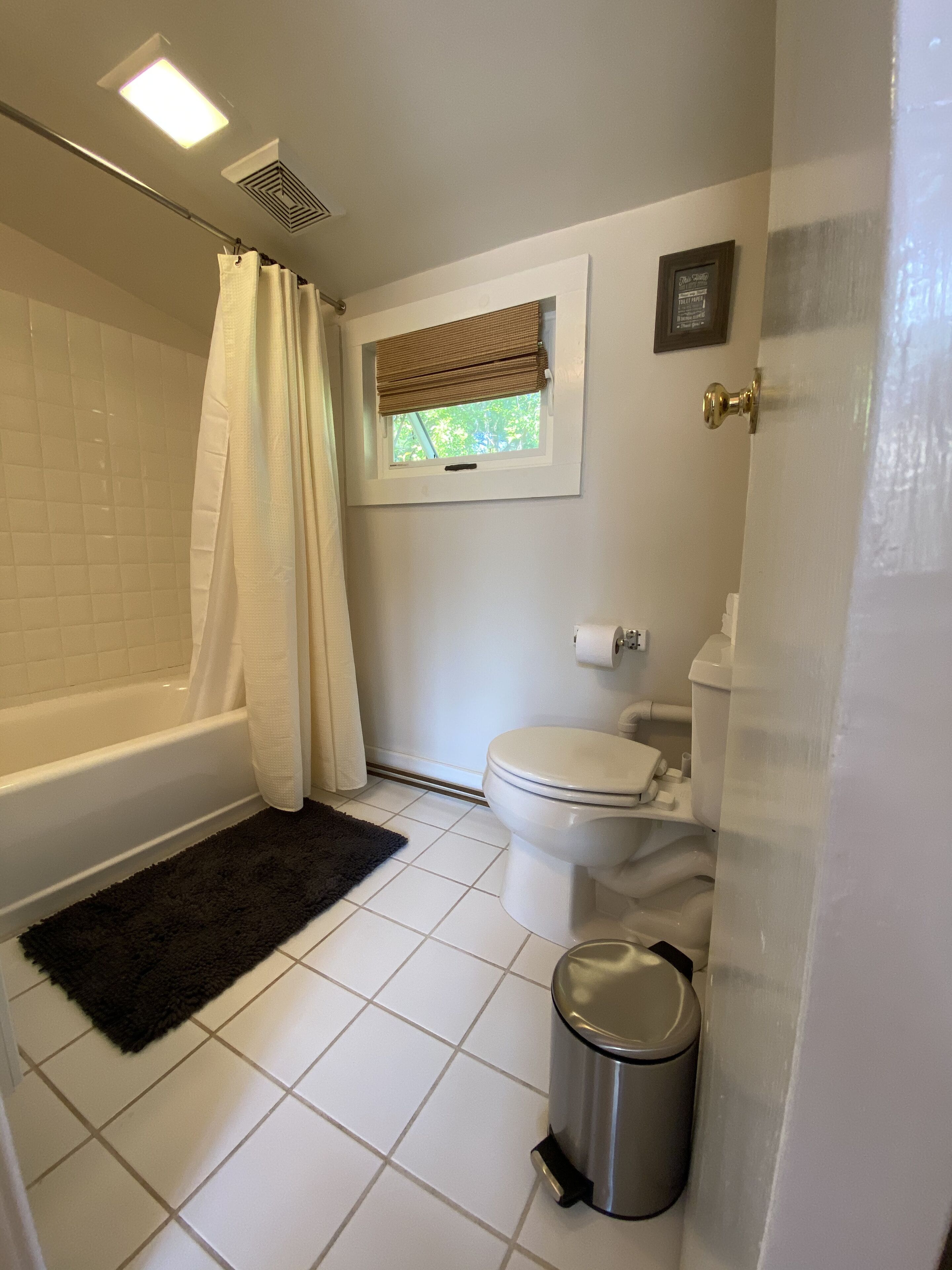 A bathroom with a bathtub, toilet, and a window with a view.