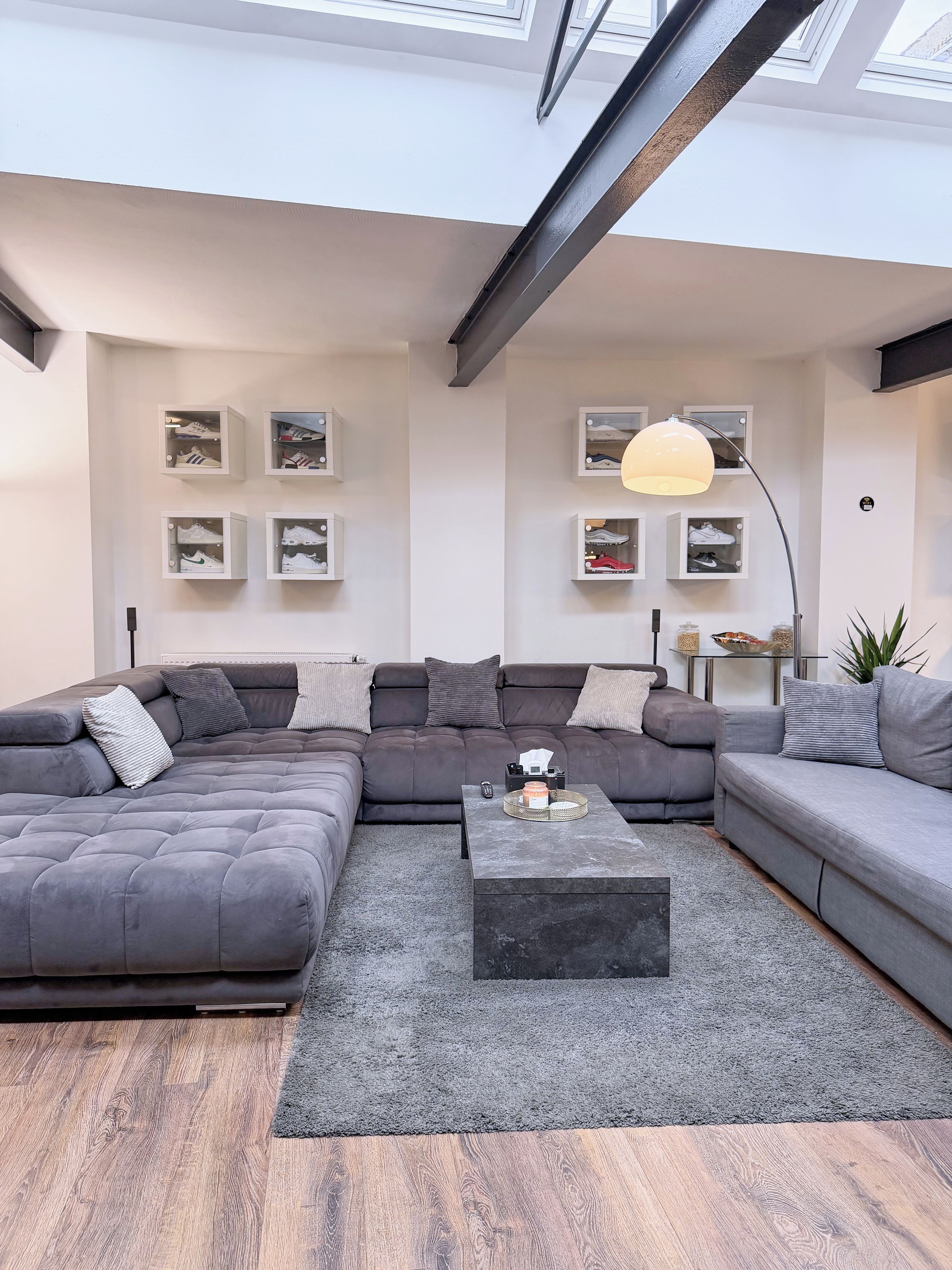 A modern living room with a sectional sofa, a coffee table, and shoe storage on the wall.