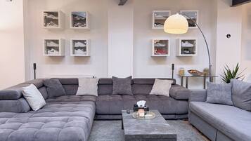 A modern living room with a sectional sofa, a coffee table, and shoe storage on the wall.