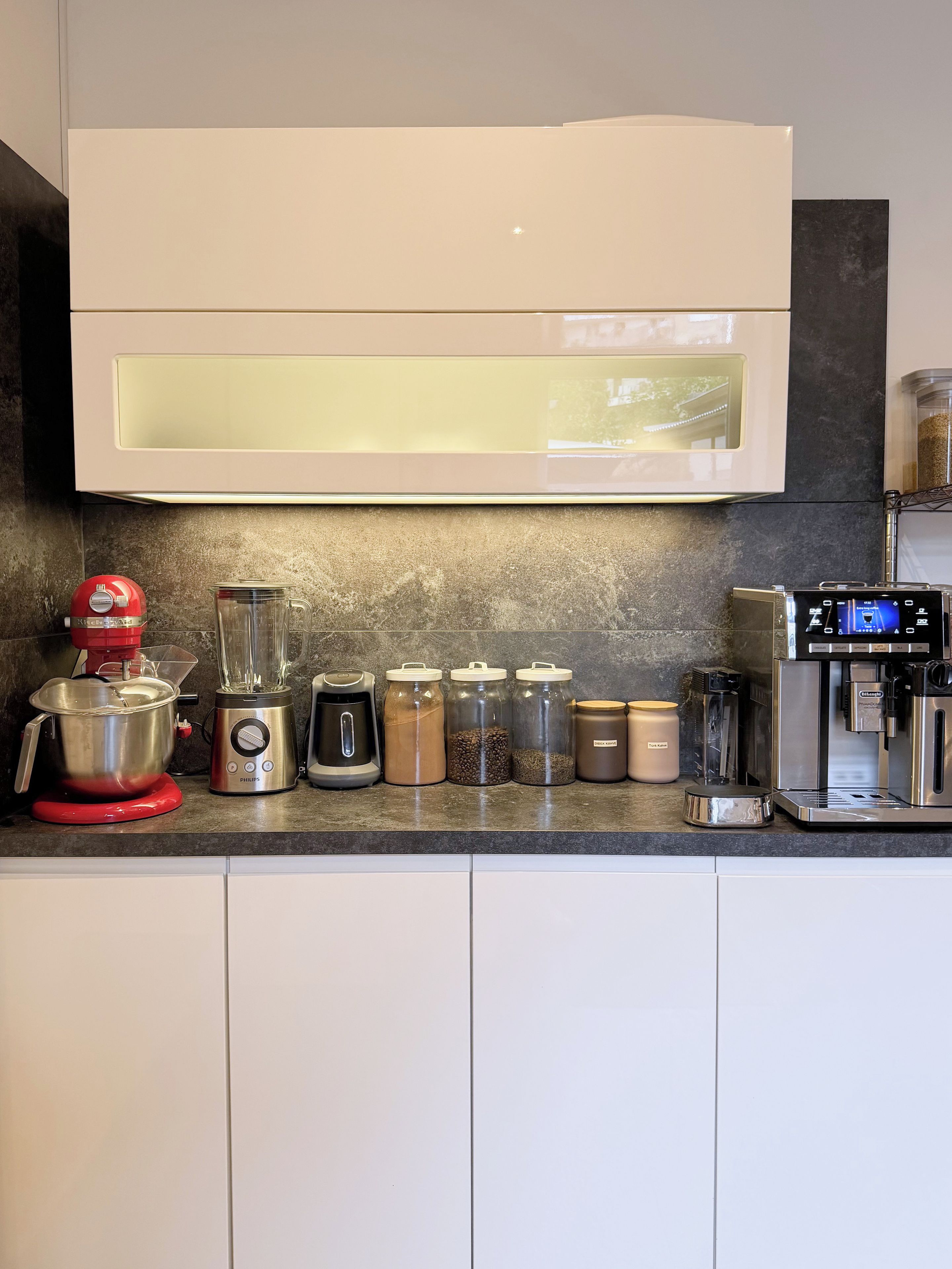 Una cocina con diseño moderno, que incluye una batidora de pie, una cafetera y varios recipientes de almacenamiento.