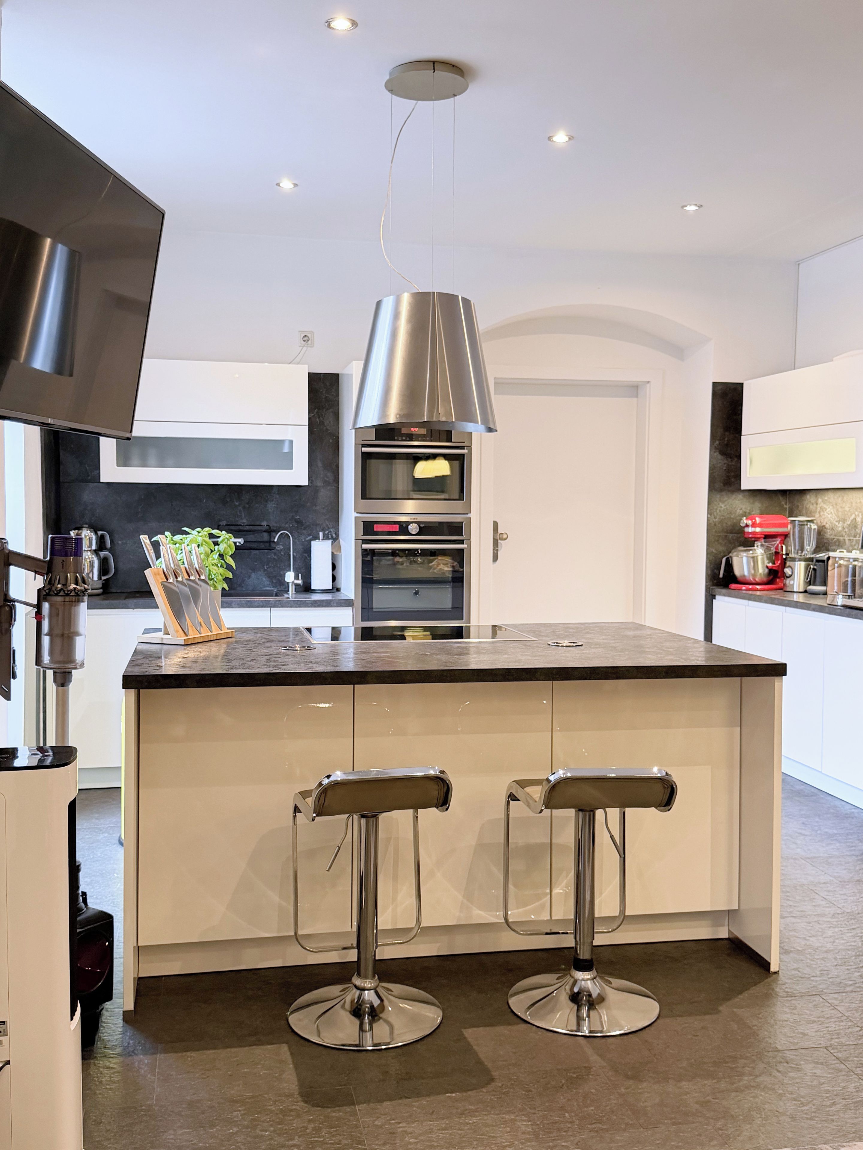 A modern kitchen with a central island, stainless steel appliances, and a pendant light.