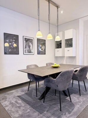 Un comedor moderno con una mesa rectangular, seis sillas tapizadas e iluminación colgante.