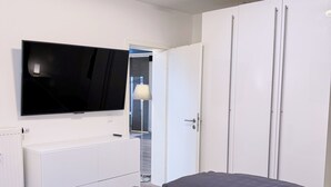 A modern bedroom with a bed, a TV, a radiator, and a skylight. - Stylish 168 m² loft in the heart of Düsseldorf (Stadtbezirk 3)
