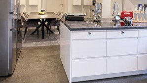 A modern kitchen with a central island, built-in appliances, and a flat-screen TV mounted on the wall. - Stylish 168 m² loft in the heart of Düsseldorf (Stadtbezirk 3)