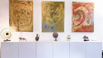 A modern interior with a white console table displaying decorative items, a ceiling light, and abstract wall art.