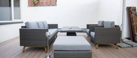 Une terrasse extérieure aménagée avec des meubles en osier, une table et un grand parasol.