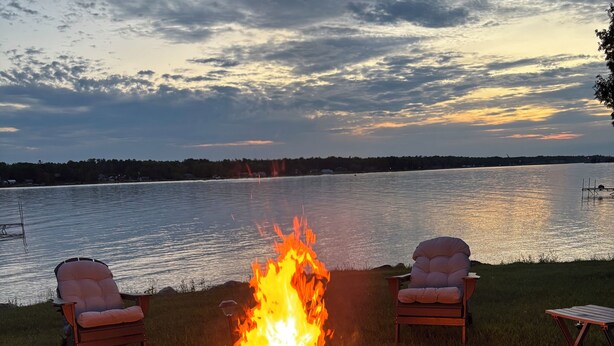 Nuotiopaikka, jossa on istuimia, järvi ja auringonlasku.