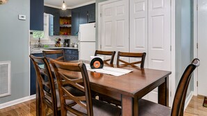 A dining area with a wooden table and chairs, a record player, and a kitchen in the background. - Down town Travelers rest walking to swamp rabbit bike trail  (Travelers Rest)