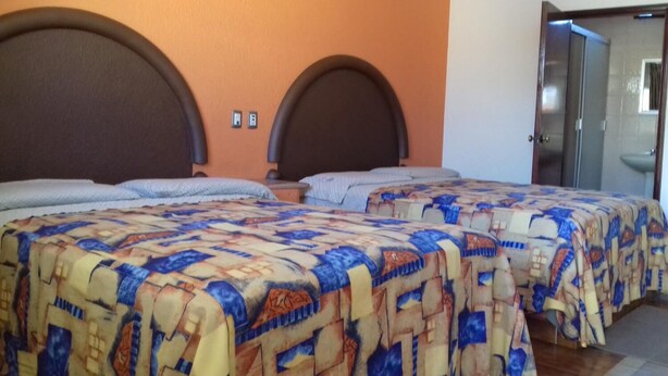 A hotel room with two beds, each with a headboard, a bathroom with a sink, and a door leading to another room. - Motel Tokio Inn (Texcoco de Mora)