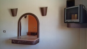 A room with a wall-mounted TV, a mirror, and two wall sconces. - Motel Tokio Inn (Texcoco de Mora)