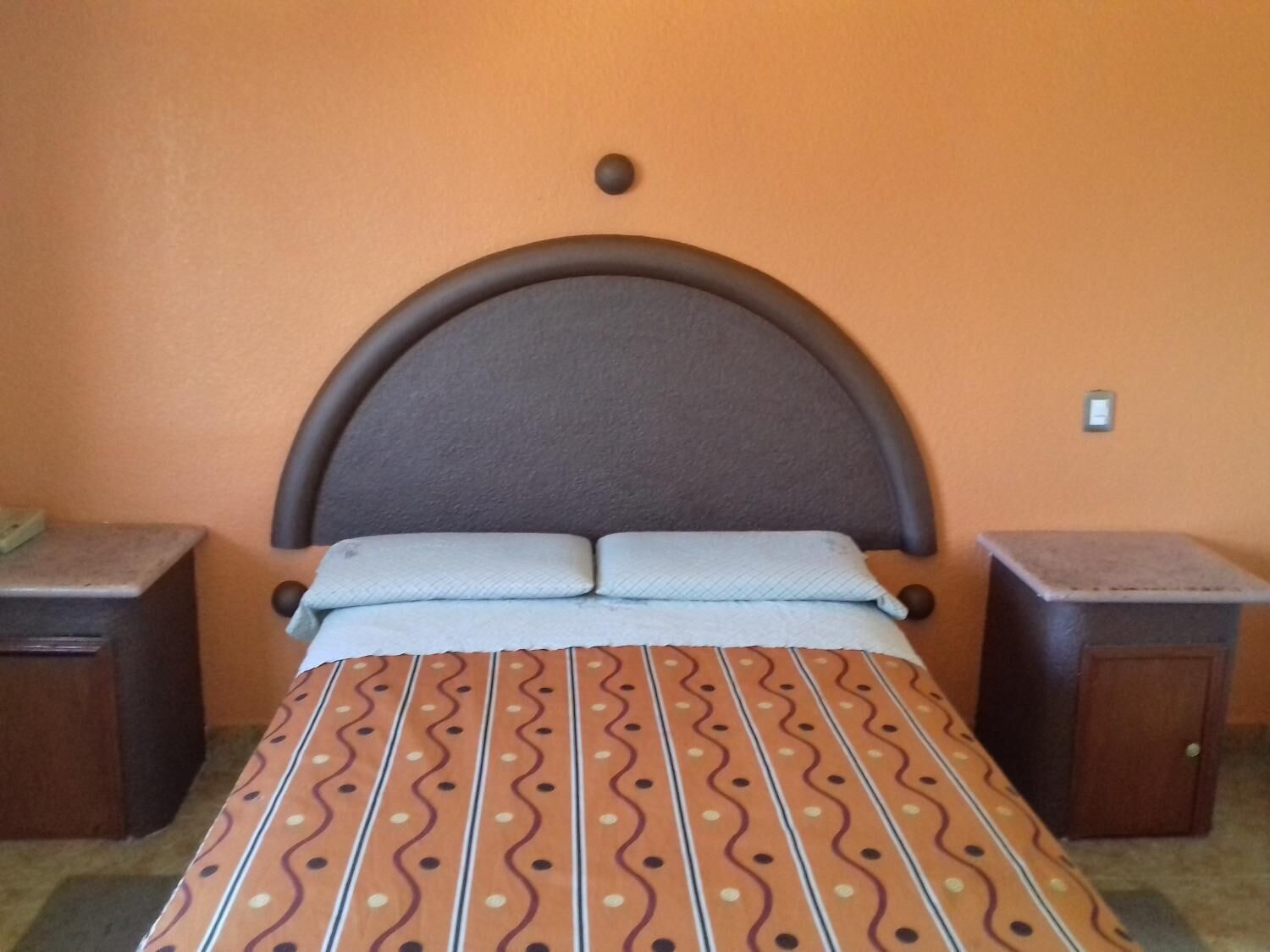 A bed with a patterned bedspread, a headboard, and two nightstands.