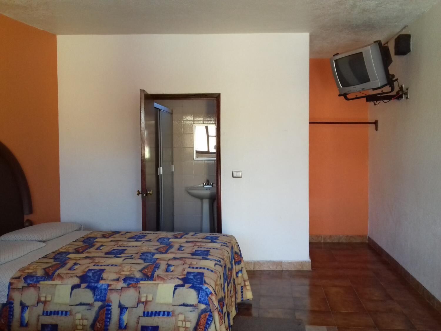 Una camera da letto con un letto, una porta che dà su un bagno e una televisione montata a parete.