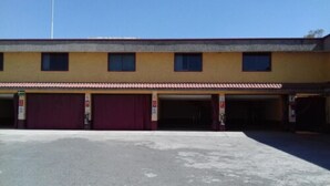 A building with three garage doors, a flat roof, and a clear sky. - Motel Tokio Inn (Texcoco de Mora)