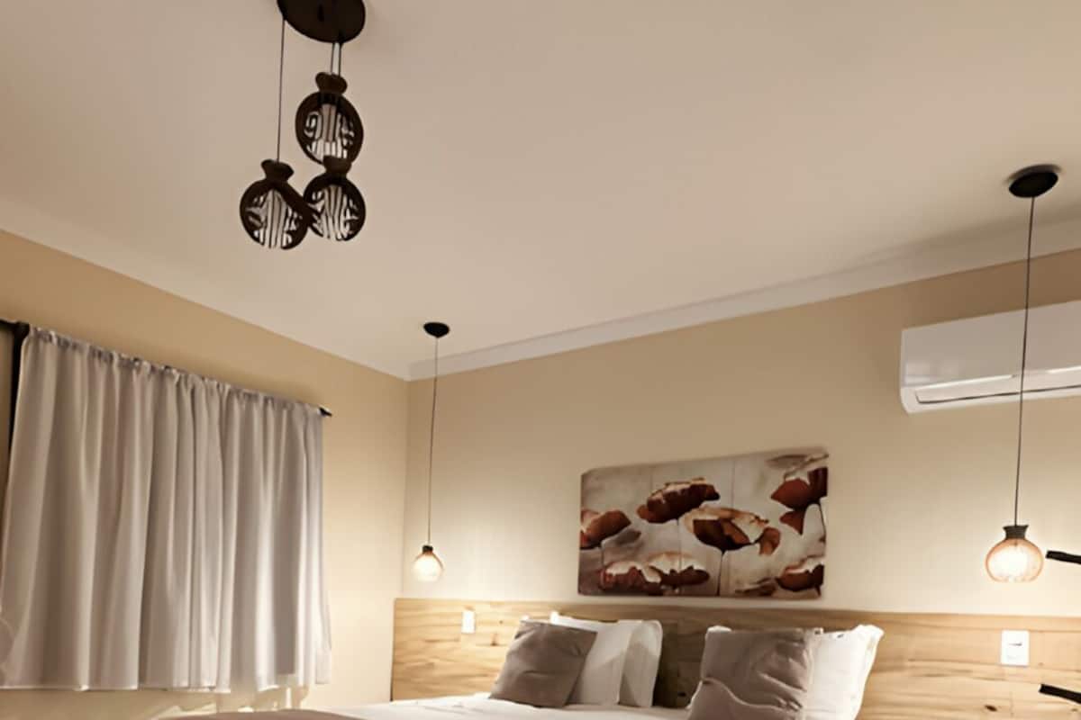 Ein modernes Schlafzimmer mit einem großen Bett, Nachttischen, einer Bank und einer Deckenleuchte.