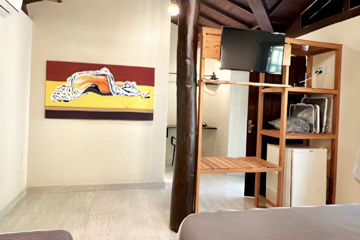 Ein Hotelzimmer mit zwei Betten, einer Holzbalkendecke, einem Bild an der Wand und einem Fernseher auf einem Regal.