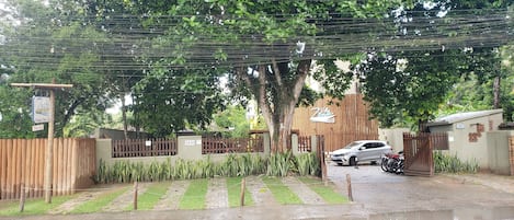 A gated residential area with a paved driveway, parked cars, and a motorcycle.