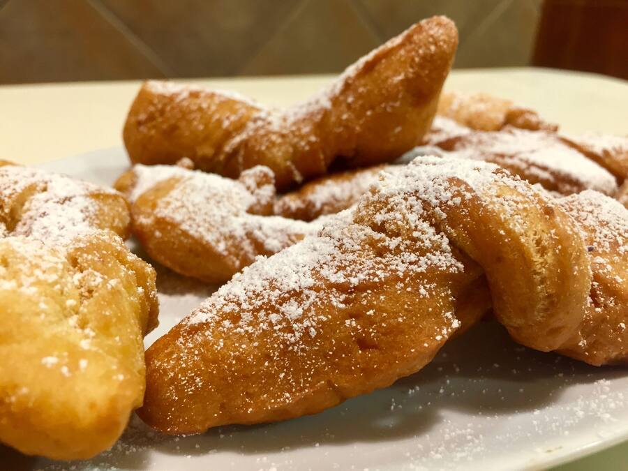 Un plato de buñuelos espolvoreados con azúcar glas.