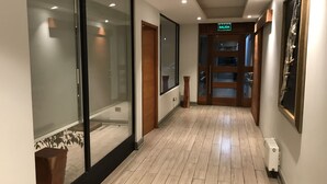 A hallway with wooden flooring, glass doors, and a 'SALIDA' sign. - Hotel Turismo Temuco (Temuco)