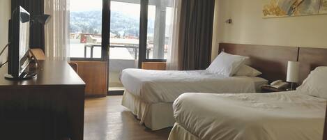 Habitación de hotel con dos camas, un escritorio, una silla, un teléfono y un cuadro en la pared.