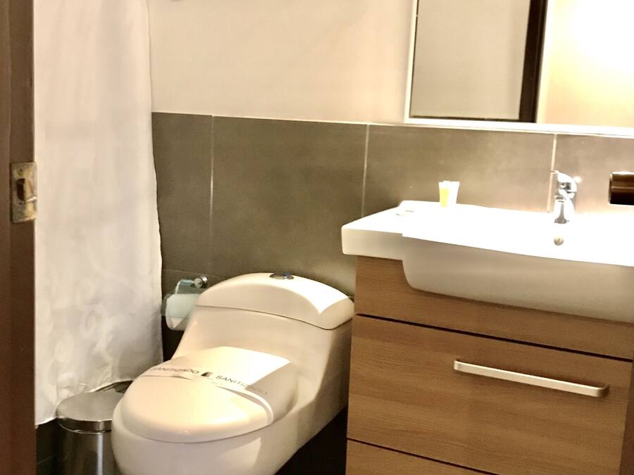 A bathroom with a white toilet, a sink with a mirror above it, and a trash can.