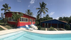 Un bâtiment rouge et bleu avec une piscine, entouré de palmiers.