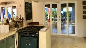 Une cuisine moderne équipée d’une cuisinière à gaz, d’un tableau noir avec des inscriptions et donnant sur une terrasse extérieure.