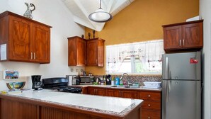 A kitchen with wooden cabinets, a stainless steel refrigerator, a microwave, and a coffee maker.