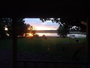 A view of a lake at sunset with trees and a dock.