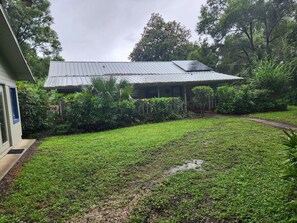 A building with a metal roof, surrounded by lush greenery and a grassy yard. - Peaceful Lakefront Getaway, Stunning Sunsets & Waterfront Relaxation (Keystone Heights)