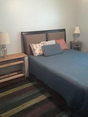 A bedroom with a bed, a nightstand, a lamp, and a striped rug. - Peaceful Lakefront Getaway, Stunning Sunsets & Waterfront Relaxation (Keystone Heights)